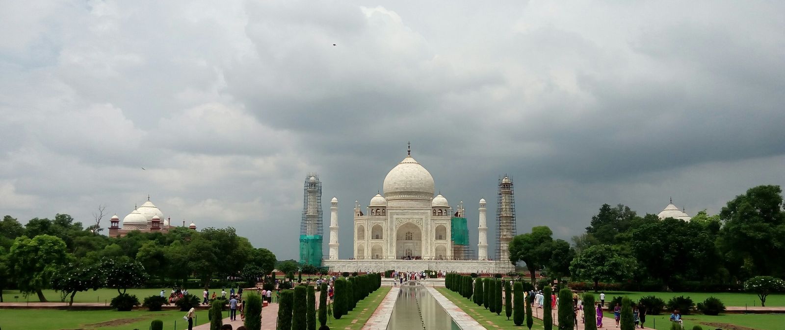 The Taj Mahal under dark monsoon clouds with the garden green after rain