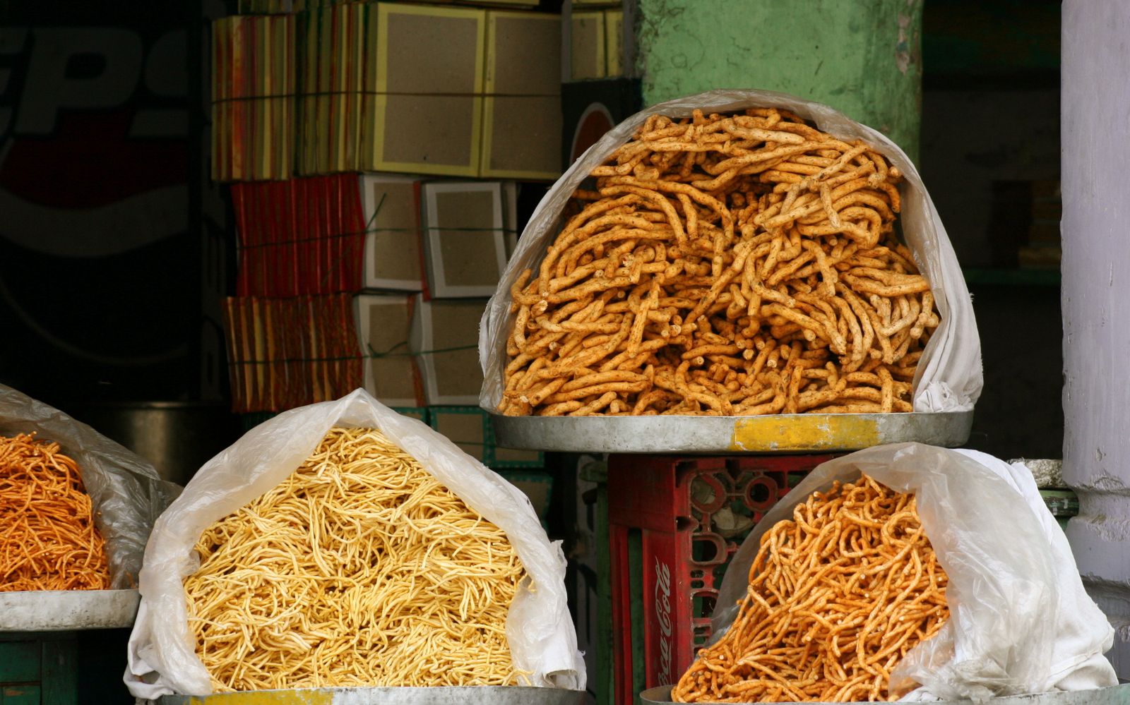 Heaps of golden Bikaneri bhujia and other savoury snacks on a shop counter