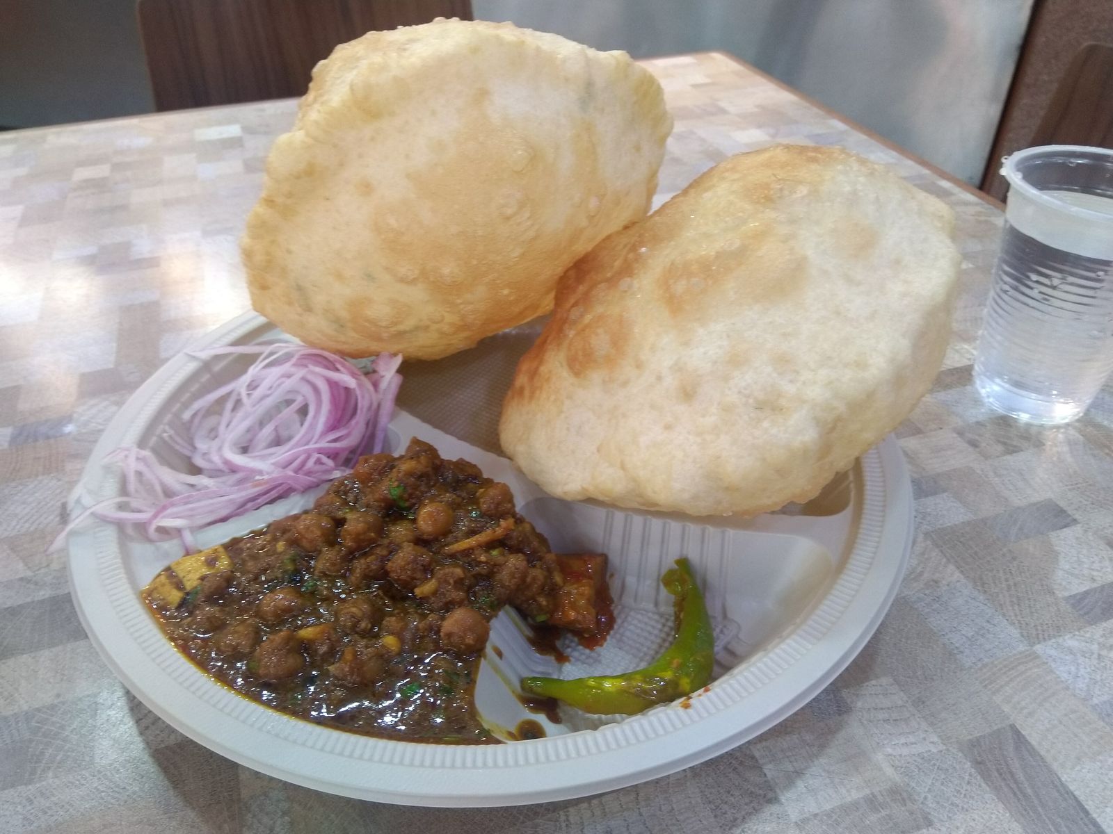 A plate of chole bhature with puffed fried bread, spiced chickpeas, onions and pickle in Delhi