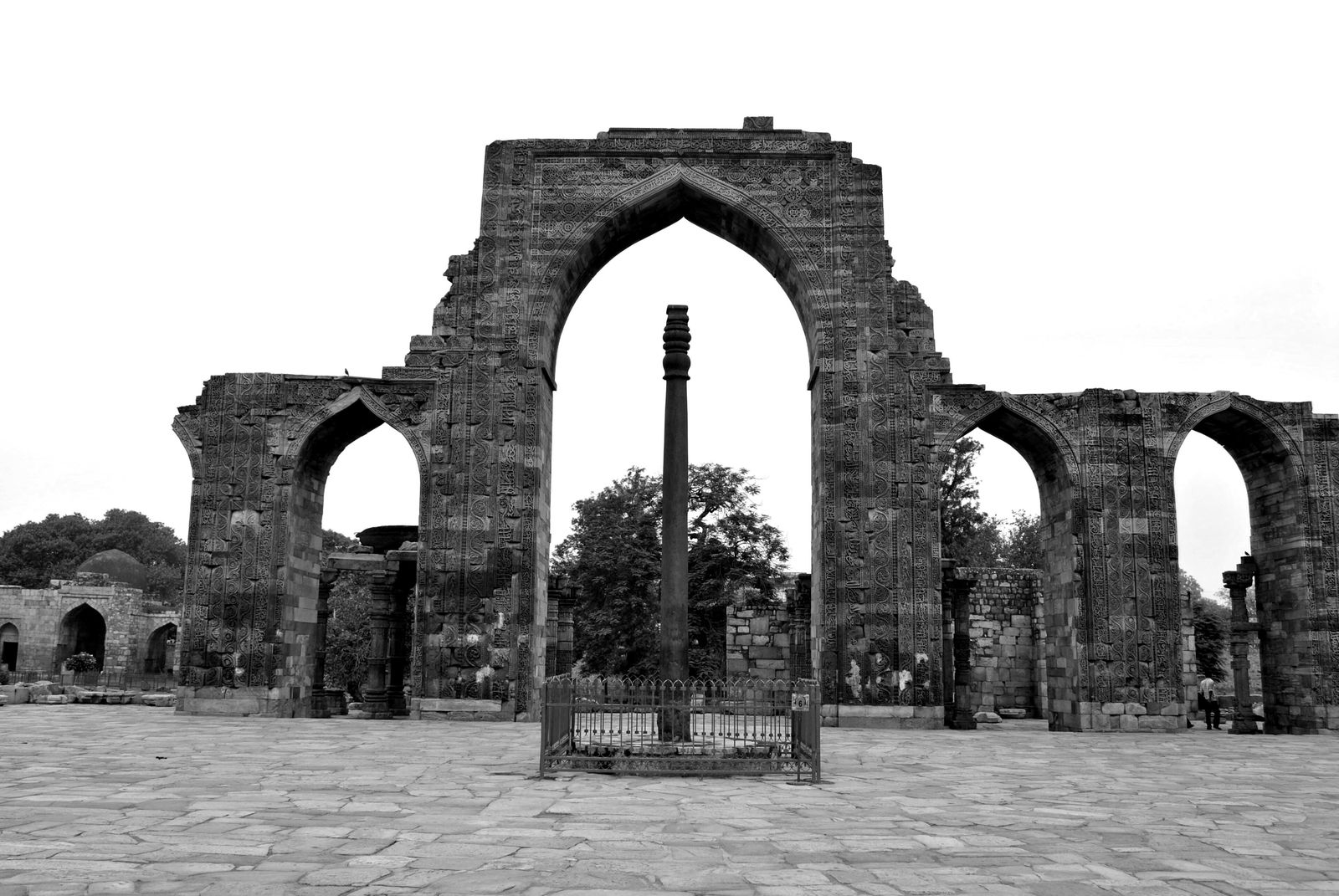 The Iron Pillar of Delhi standing in the courtyard of the Quwwat-ul-Islam mosque among carved stone colonnades