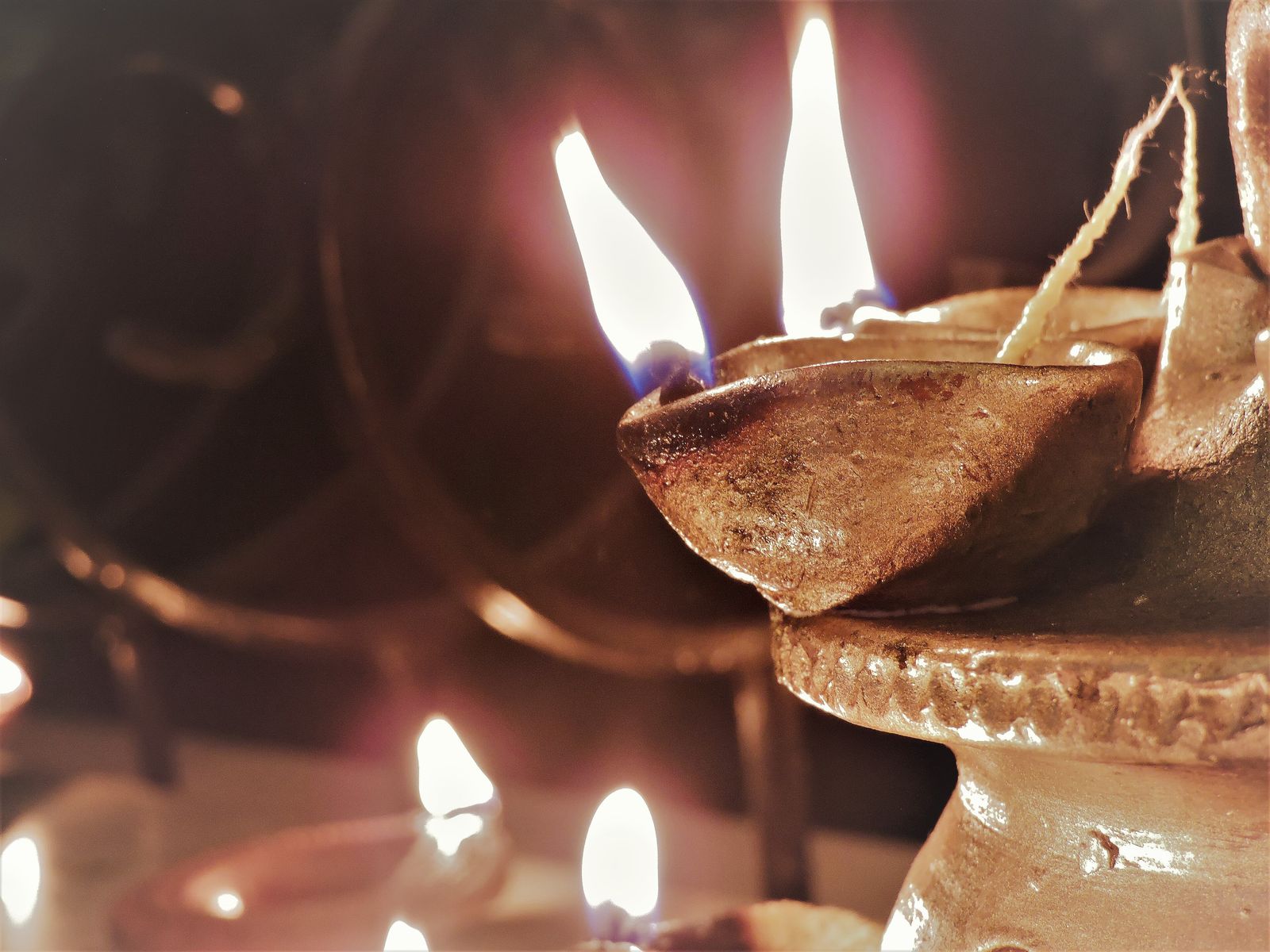 Rows of small clay diya lamps burning with oil and cotton wicks for Diwali