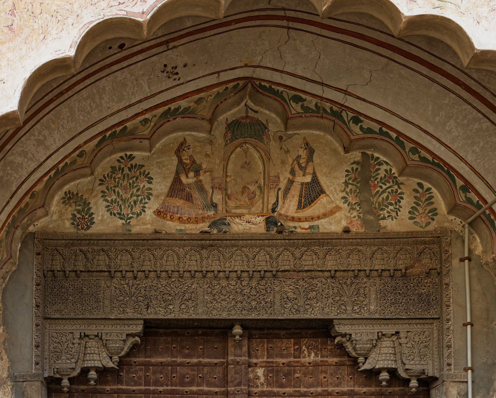 A painted Ganesh tympanum above a carved wooden door lintel at the Ganesh Haveli in Fatehpur