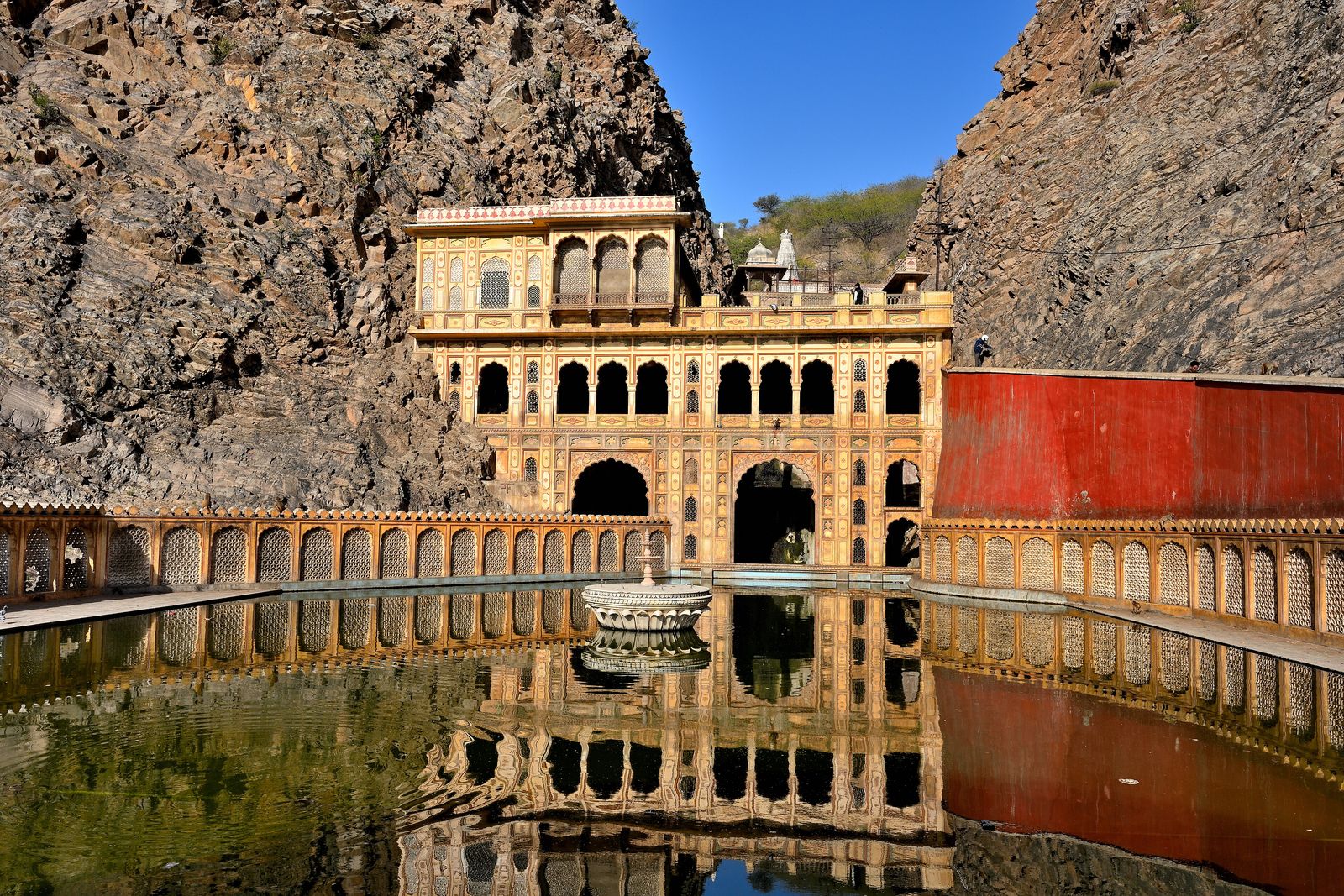 Pilgrims at a sacred stone tank at Galtaji, Jaipur, with temple pavilions rising above the water