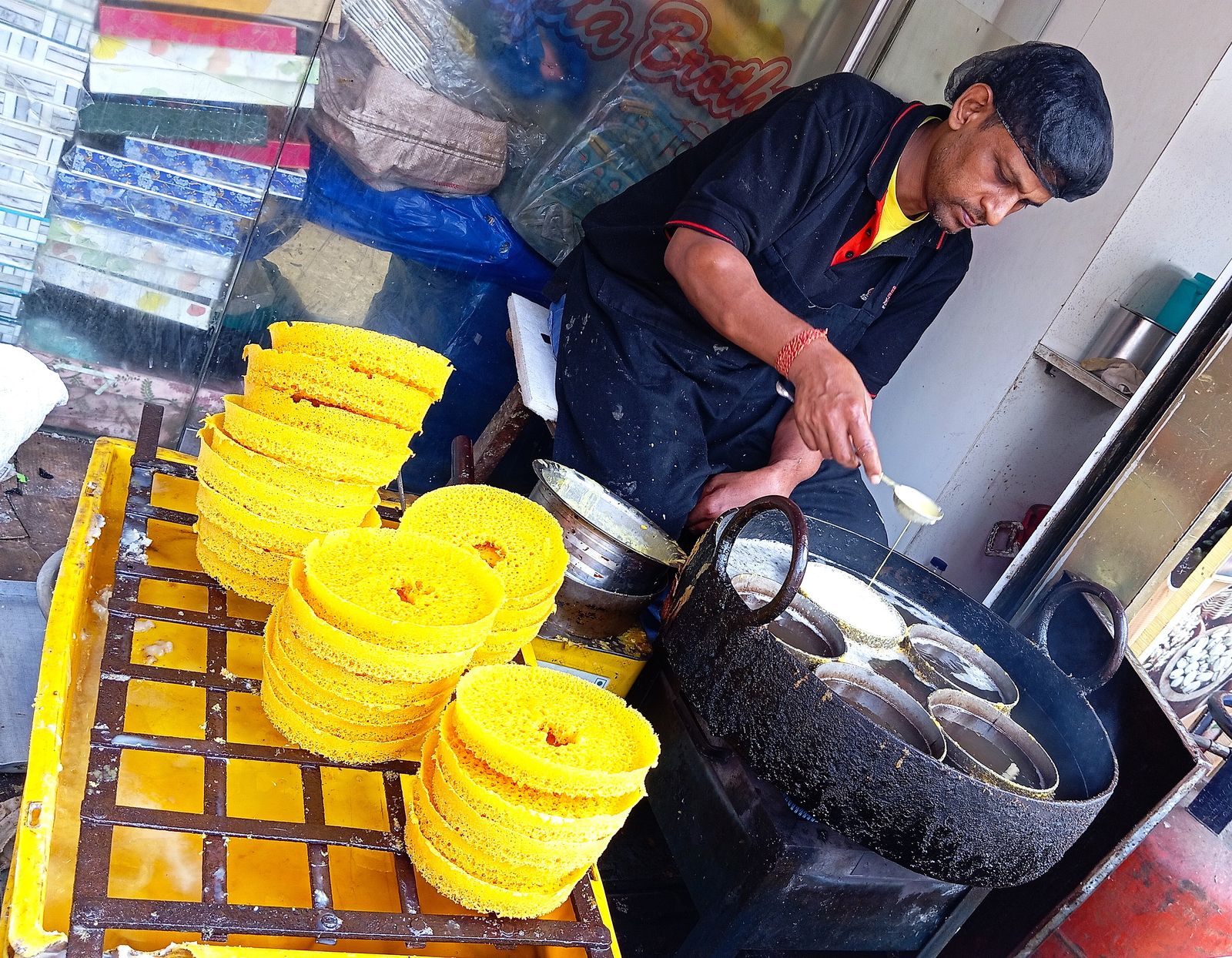 A halwai lifting golden discs of ghevar from hot ghee at a sweet stall