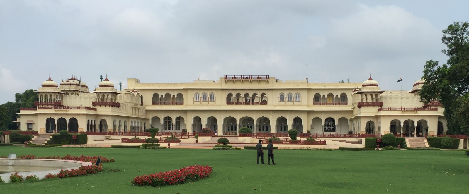 The cream and white facade of Rambagh Palace in Jaipur seen across its lawns