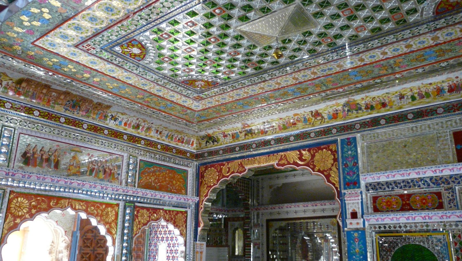 A painted and mirrored room inside Patwon ki Haveli in Jaisalmer, with carved arches and wall paintings