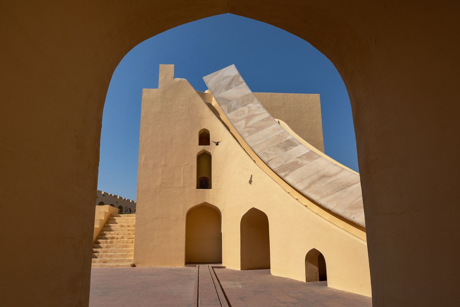 The arched gateway of Jaipur's Jantar Mantar framing a giant stone sundial