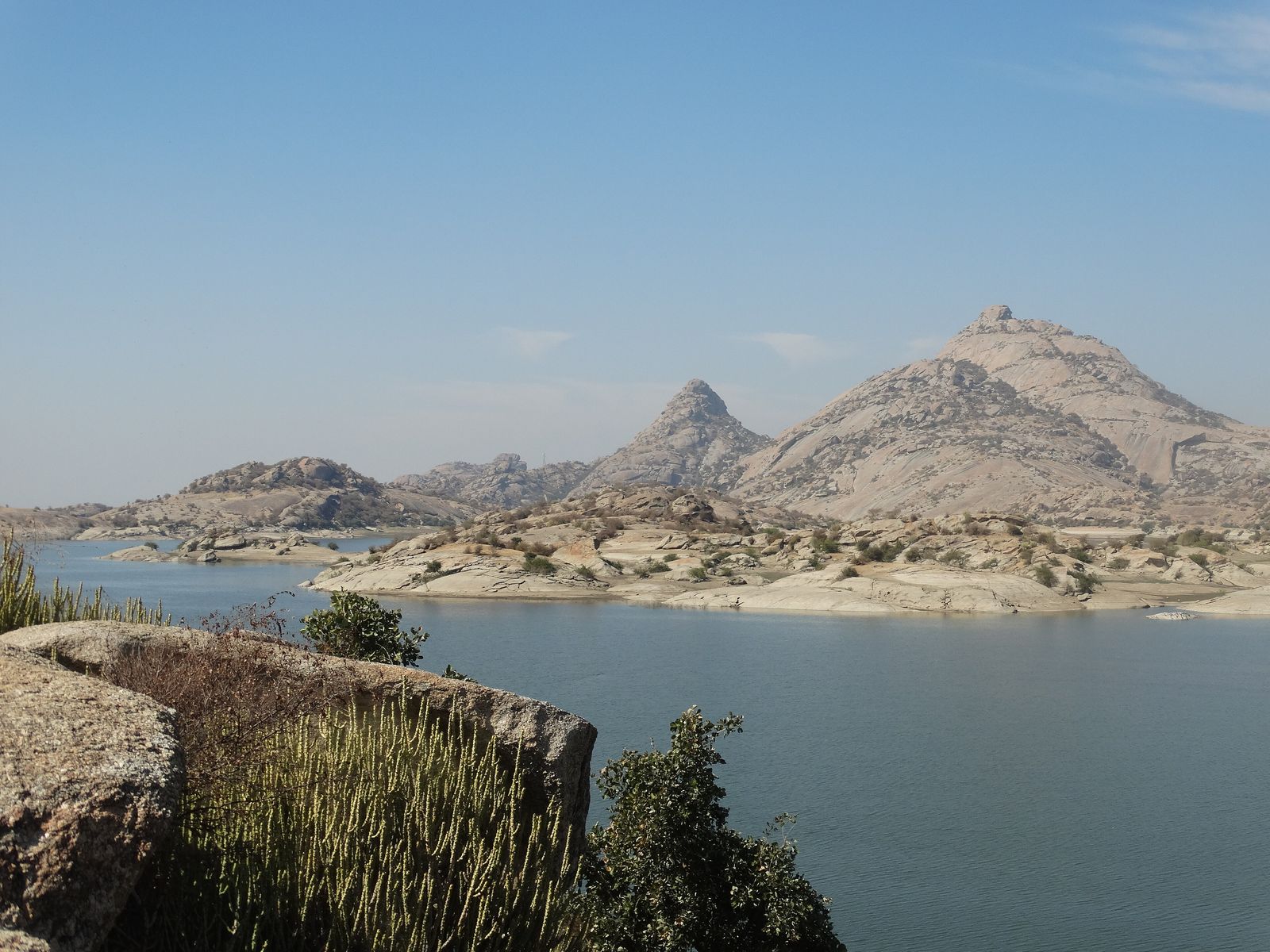The wide waters of the Jawai Bandh reservoir at sunrise with granite hills on the far shore