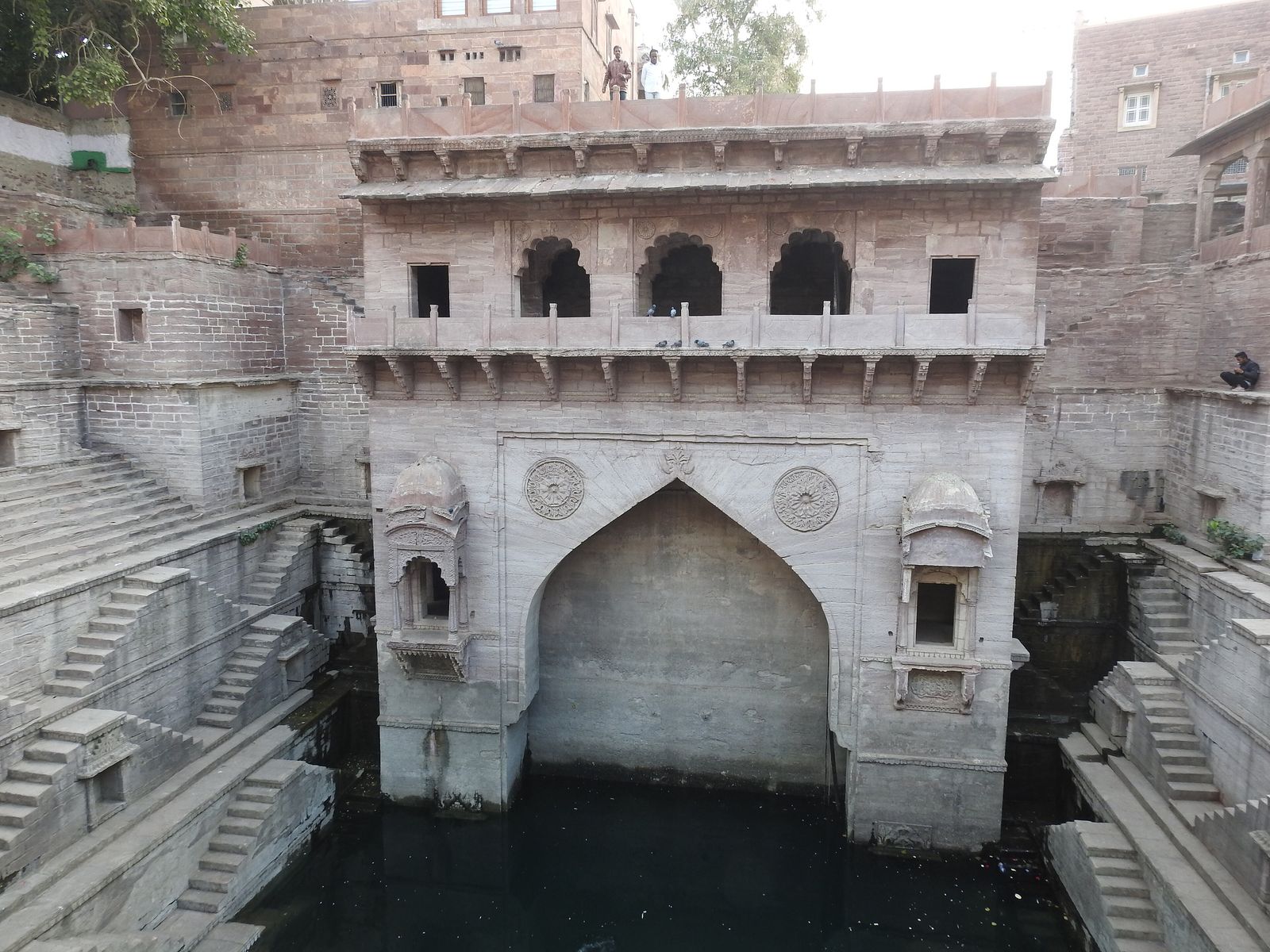 Carved stone elephants and niches set into the red sandstone walls of Toorji ka Jhalra stepwell in Jodhpur