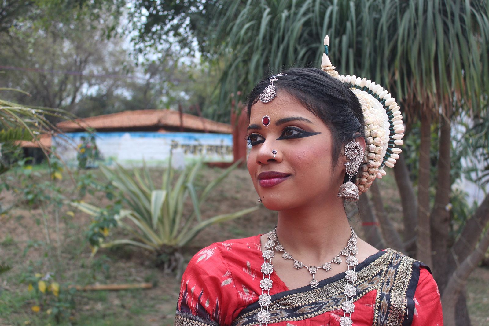 A classical dancer performing on the open-air stage of the Khajuraho Dance Festival with lit temples behind