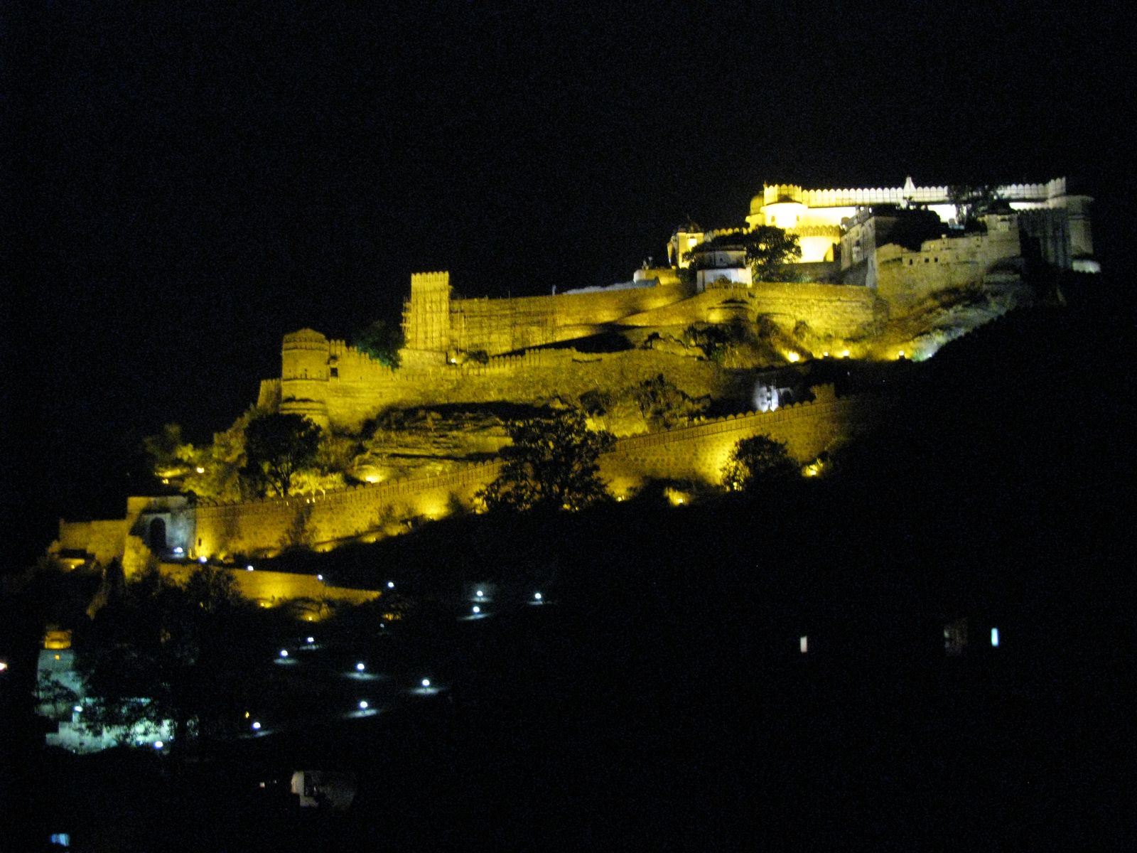 Kumbhalgarh Fort lit up at night against the dark Aravalli hills
