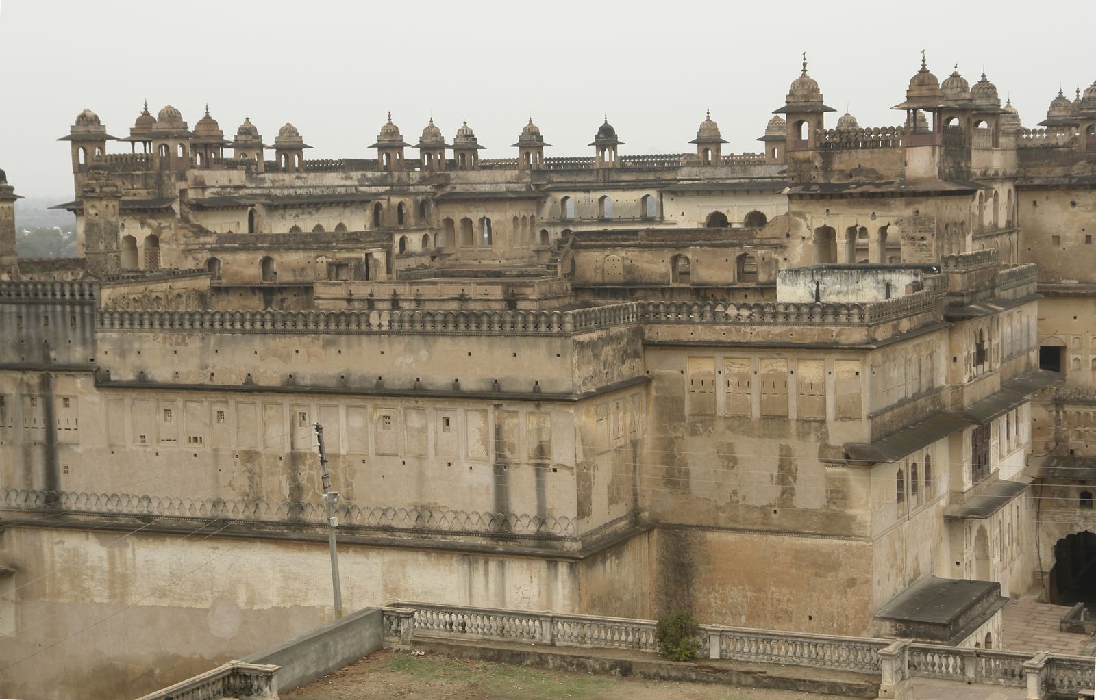 The stone courtyard and upper galleries of the Raja Mahal inside Orchha Fort