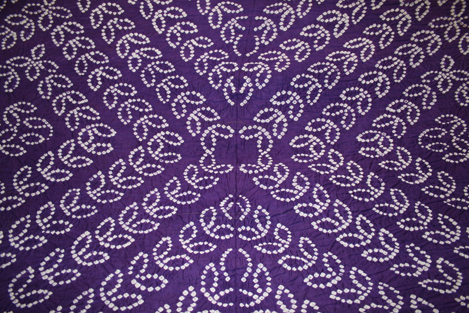 Bandhani tie-dyed cloth, its white dots tied by hand on purple