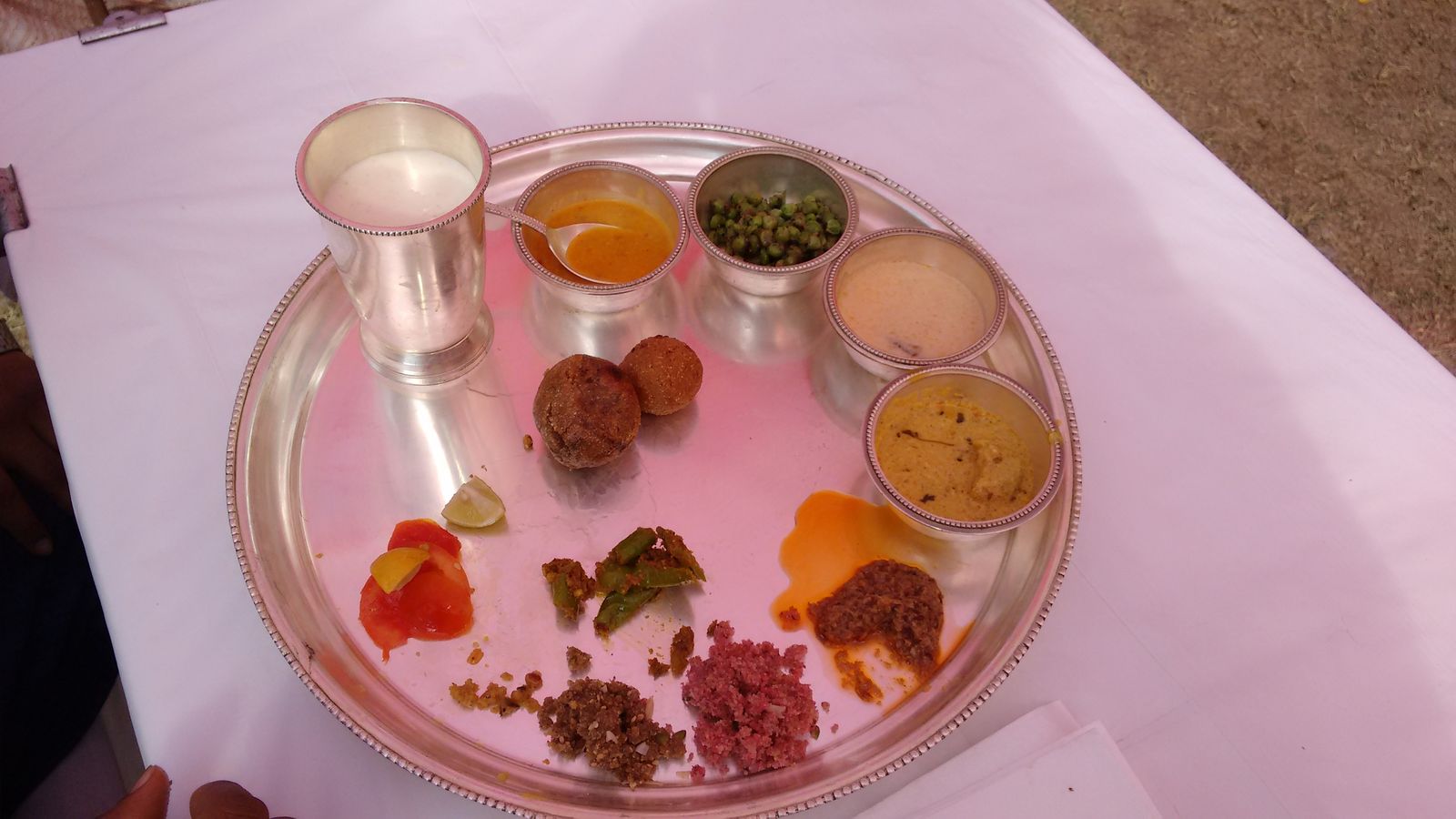 Round baked wheat baatis served with dal, ghee and sweet churma on a brass plate in Rajasthan