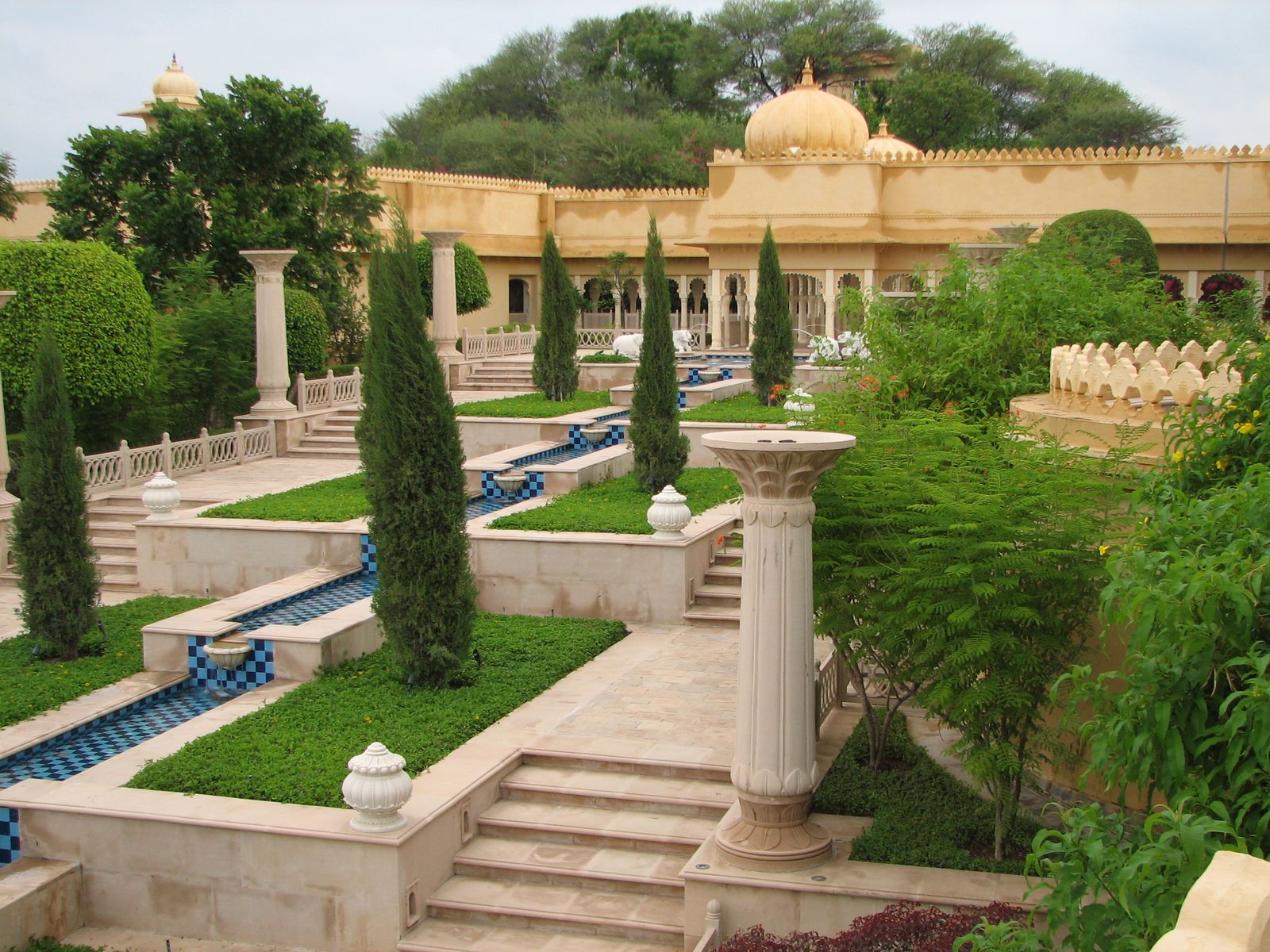 The central courtyard of The Oberoi Udaivilas, with arched colonnades around a still pool of water